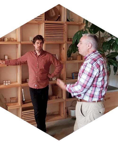 Nicolas Geant and Alex Mclean speak in front of a display of honey and hive products