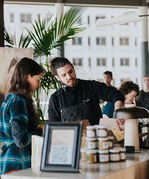 A beekeeper speaks with a woman in front of a display of honey jars. benefits of green building certifications
